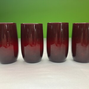 Könnte beinhalten: Vier Weingläser ohne Stiel mit einem tiefroten Ombre-Design. Die Gläser haben einen abgerundeten Boden und eine gerade, zylindrische Form, ideal zum Servieren von Wein oder anderen Getränken. Die Gläser sind aus Glas.