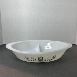 May include: White divided casserole dish with a green floral design around the rim.