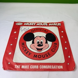 Könnte beinhalten: Vintage rote und weiße Schallplattenhülle von Mickey Mouse March. Die Hülle zeigt ein lächelndes Mickey Mouse-Gesicht in der Mitte, umgeben von den Worten "Mickey Mouse Club" und "Official". Der Text "The Mike Curb Congregation" steht unten.