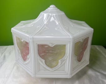 Könnte beinhalten: Weißer, achteckiger Lampenschirm aus Glas mit dekorativer Oberseite und Paneelen. Die Paneele weisen ein schildartiges Design mit rosa und gelben Farbtönen auf. Der Schirm ist wahrscheinlich für eine Deckenleuchte oder eine Tischlampe.