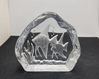May include: A clear glass sculpture featuring two etched fish swimming among aquatic plants. The sculpture is in a rectangular shape with rounded edges. Bubbles are etched around the fish.