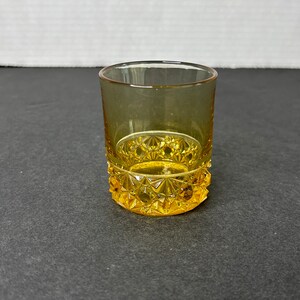 Könnte beinhalten: Ein gelbes Glas-Schnapsglas mit einem Diamantenmuster um den Boden.