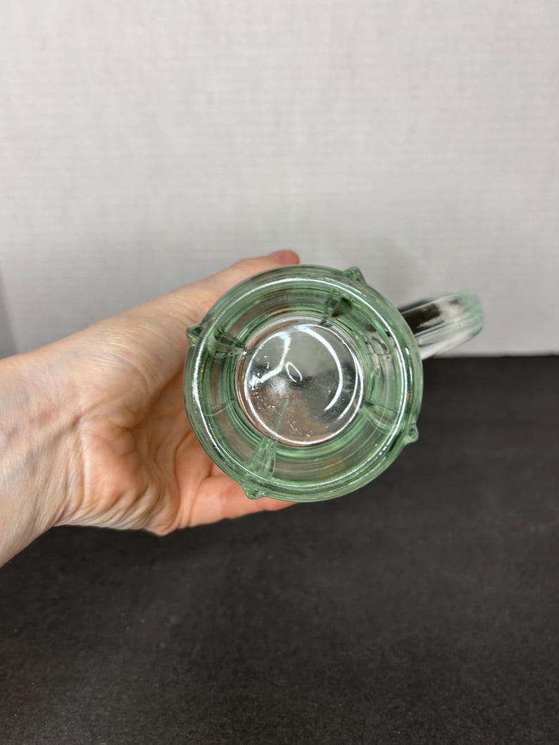 May include: A clear glass mug with a green tint and a handle. The mug has a textured, ribbed design.