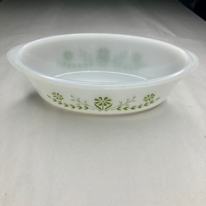 May include: White oval baking dish with a green floral design. The dish has a rim around the top edge.