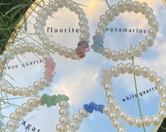 May include: Six pearl bracelets with different colored gemstones. The bracelets are labeled "fluorite", "aquamarine", "rose quartz", "white quartz", "agate", and "blue quartz".