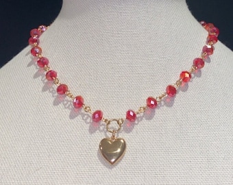 May include: A gold heart charm necklace with red crystal beads.