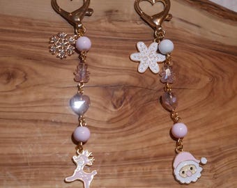 May include: Two Christmas-themed keychains with gold-colored heart-shaped clasps. One keychain features a snowflake charm, pink beads, and a reindeer charm. The other has a snowflake charm, pink beads, and a Santa charm.