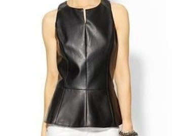 Op de afbeelding: Zwart mouwloos topje met een peplum zoom. De top heeft een ronde halslijn en een klein sleutelgatdetail aan de voorkant. Het model draagt een witte broek en houdt een zwarte clutch vast.