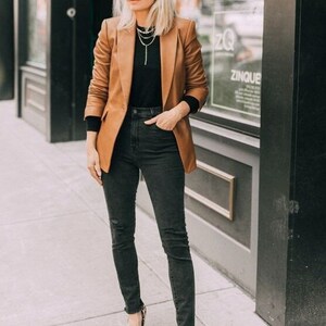 May include: A woman wearing a brown blazer, black turtleneck, black jeans, and leopard print heels.