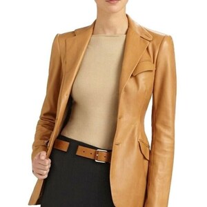 May include: A tan leather blazer with a single button closure and two flap pockets. The blazer has a fitted silhouette and a notched collar.