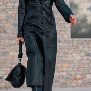 May include: A long black leather coat with a button-up front and a fitted silhouette.