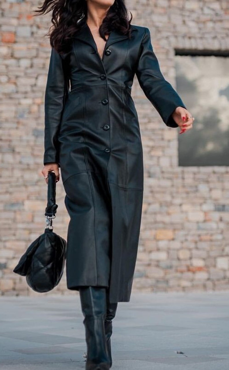 May include: A long black leather coat with a button-up front and a fitted silhouette.
