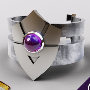 Puede incluir: Una pulsera de metal plateado con una gema púrpura en el centro. La pulsera tiene un diseño geométrico y está hecha de dos bandas.