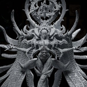 May include: A detailed, grey, 3D printed figurine of a female demon with long, flowing wings and intricate details. The demon is standing on a circular base with a raised design.