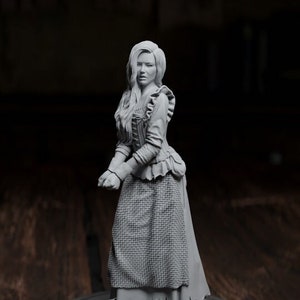 May include: A grey painted miniature figurine of a woman wearing a long dress and holding her hands in front of her. The figurine is standing on a black circular base. A yellow 20-sided die is in the background.