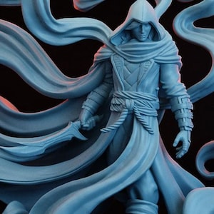May include: A grey 3D printed miniature of a hooded figure with a flowing cloak and a dagger. The figure is standing on a base with the text "MESKOR SHADOW MANIPULATOR ASSASSIN" and "JULY/24".