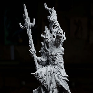 May include: A detailed grey resin miniature of a creature with a staff, standing on a base with swirling details. The miniature is posed with its arms raised and its head tilted back. A brown and gold dice is in the foreground.
