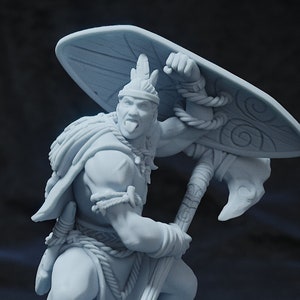 May include: A light grey figurine of a warrior in a battle stance, holding an axe and shield. The warrior wears a helmet, cape, and rope detailing. The shield has a spiral design. The figurine is on a round base.