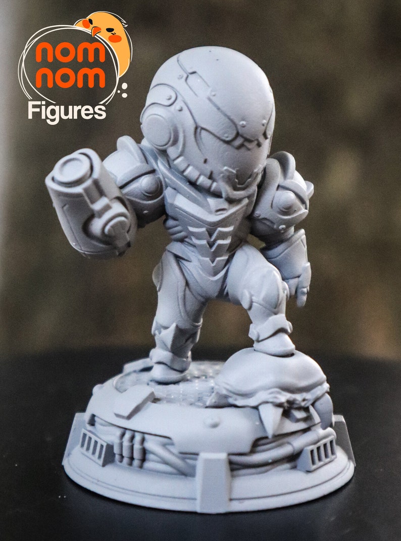 May include: A gray, 3D printed figurine of a video game character, Samus Aran from Metroid, in a standing pose holding a weapon. The figurine is on a base with a textured surface.