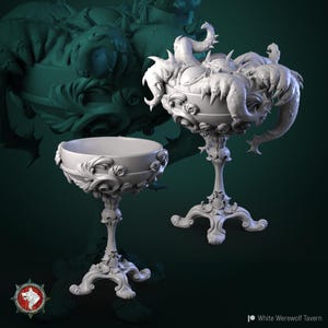 May include: Two ornate silver goblets, one with a detailed design and the other with a tentacled creature design.