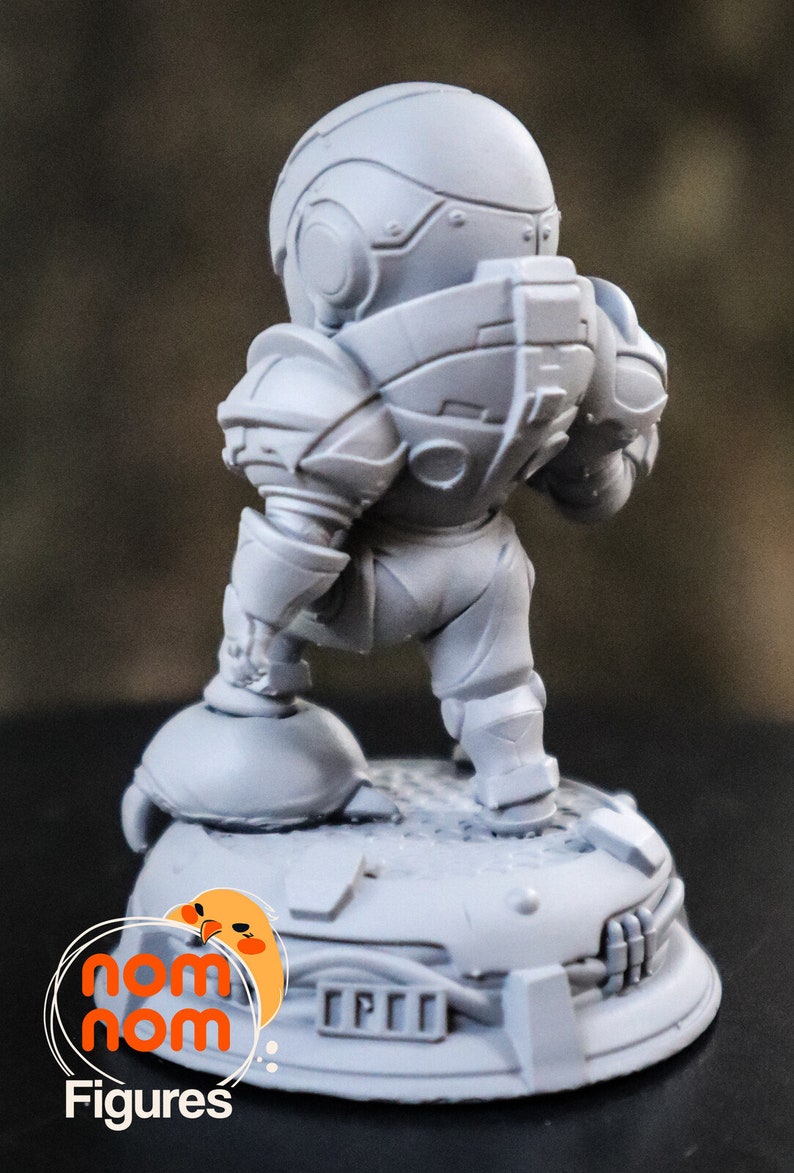 May include: A gray, detailed, 3D printed miniature figure of a robot wearing a helmet and standing on a round base. The base has a textured surface and the text "CPT" is printed on it.