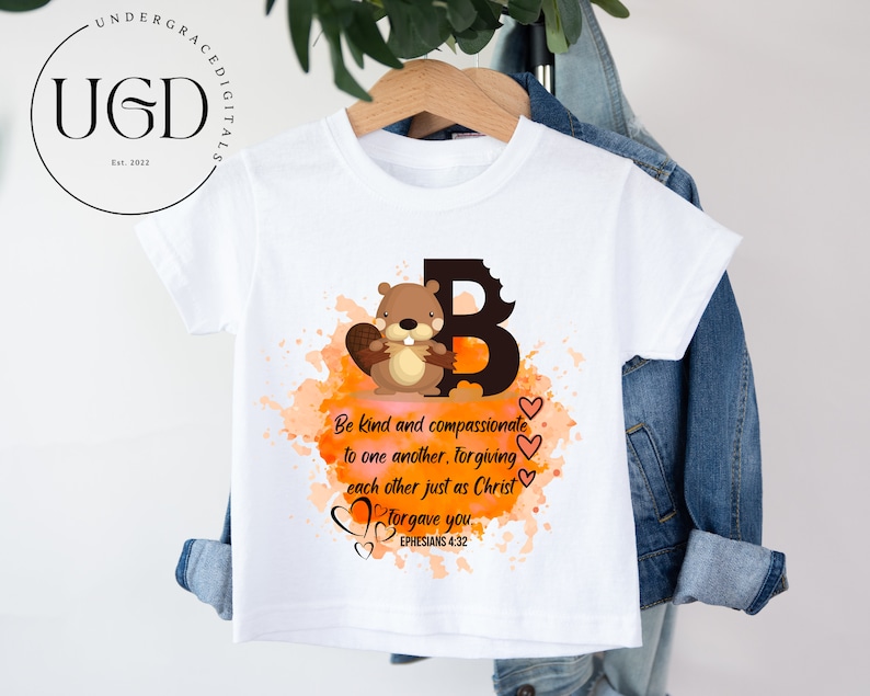 May include: White t-shirt with a brown cartoon beaver holding a branch. The beaver is in front of a large letter B with orange and brown watercolor splatters. The text "Be kind and compassionate to one another, forgiving each other just as Christ forgave you. Ephesians 4:32" is printed below the beaver.