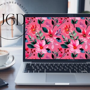 Op de afbeelding: Een laptop toont een levendig bloemenpatroon op het scherm. Het ontwerp toont roze en rode bloemen met groene bladeren en bessen tegen een roze achtergrond. Het logo "UGD" en "Est. 2022" zijn zichtbaar.