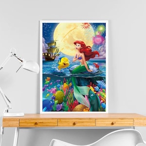Peut inclure: Une illustration color&eacute;e d'Ariel, la Petite Sir&egrave;ne, assise sur un rocher dans l'oc&eacute;an. Elle est entour&eacute;e de poissons et de coraux. La lune est en arri&egrave;re-plan avec des feux d'artifice.
