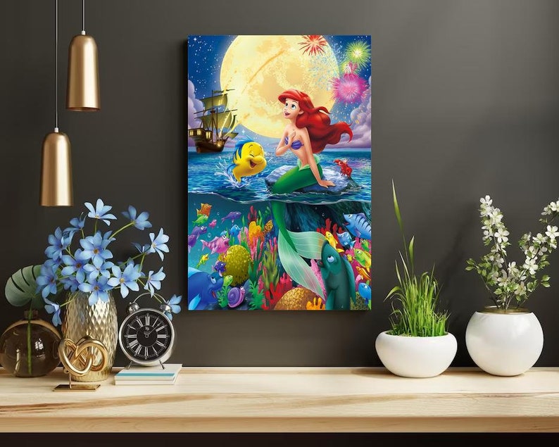 Peut inclure: Une illustration color&eacute;e d'Ariel, la Petite Sir&egrave;ne, nageant dans l'oc&eacute;an avec Polochon. La sc&egrave;ne comprend un navire, une pleine lune et des feux d'artifice.