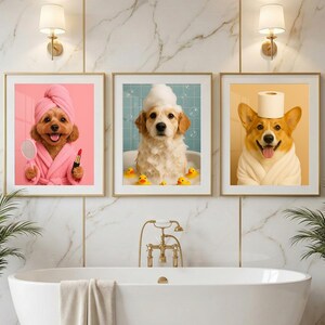 May include: A set of three framed wall art prints featuring dogs in a bathroom setting. The first shows a dog in a pink robe with a towel wrap, mirror, and lipstick. The second shows a dog in a bubble bath with yellow ducks. The third shows a dog in a white robe with a toilet paper roll on its head.