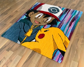 Könnte beinhalten: Rechteckiger Teppich mit einer Cartoon-Darstellung von Ash Ketchum und Pikachu. Der Teppich hat ein blaues, rotes, weißes und gelbes Farbschema. Der Hintergrund hat vertikale Streifen in Blau-, Lila- und Türkistönen.