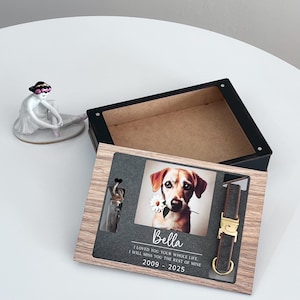 May include: A wooden box with a photo of a dog, a small glass vial, and a dog collar. The box has a gray background with the text "Bella I LOVED YOU YOUR WHOLE LIFE I WILL MISS YOU THE REST OF MINE 2009 - 2025".
