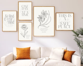 May include: Five black and white printable wall art prints with inspirational quotes and floral illustrations. The prints are framed in a light wood frame and are displayed on a white wall above a white couch with orange throw pillows.