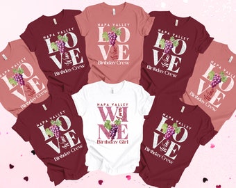 May include: Six t-shirts with a wine theme. The shirts are in maroon, pink, and white. The shirts have the text "NAPA VALLEY" and "LOVE WINE" with a bunch of grapes. One shirt says "NAPA VALLEY WINE" with a bunch of grapes. The shirts say "Birthday Crew" and "Birthday Girl".