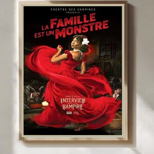 Könnte beinhalten: Poster für "Interview with the Vampire" mit einer Frau in einem roten Kleid. Der Postertext lautet "Theatre des Vampires Presents La Famille Est Un Monstre" in Weiß und Rot. Der Poster ist in einem hellen Holzrahmen gerahmt.