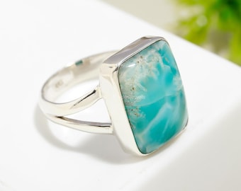 May include: A silver ring featuring a light blue and white gemstone. The gemstone is rectangular in shape and is set in a silver bezel.