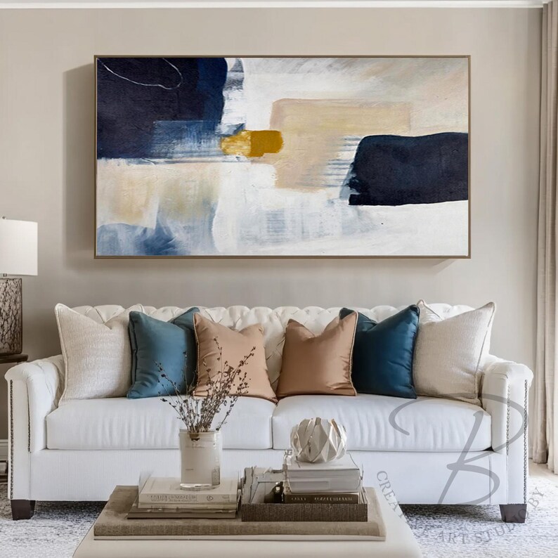 a living room with a white couch and a painting on the wall