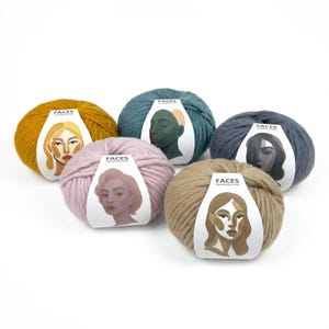 Könnte beinhalten: Fünf Wollknäuel in Senfgelb, Türkis, Rosa, Grau-Blau und Beige. Jedes Knäuel hat ein Etikett mit einer stilisierten Gesichtsillustration und dem Text "FACES THE WOOL COLLECTOR".