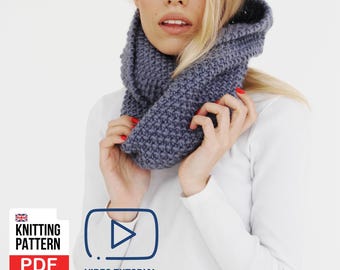 May include: A woman wearing a knitted gray cowl neck scarf. The scarf is a chunky knit design. The image also includes a "Knitting Pattern PDF" graphic and a "Video Tutorial" icon.