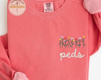May include: A watermelon-colored sweatshirt with embroidered flowers and the word "peds." The sweatshirt has a soft, fuzzy interior and the text "Personalized Gift Embroidered" on a circular sticker.