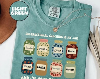May include: Light green t-shirt with the text "INSTRUCTIONAL COACHING IS MY JAM" and illustrations of jam jars. Each jar has a different word: Guide, Inspire, Grow, Model, Reflect, Coach, Support, and Empower.