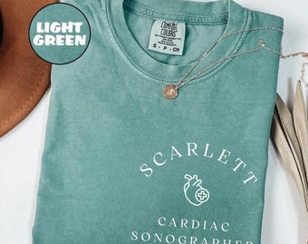 May include: A light green t-shirt with the text "SCARLETT CARDIAC SONOGRAPHER" in white. A small heart with a plus sign is above the text.