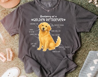 Könnte beinhalten: Dunkelgraues T-Shirt mit einer Illustration eines Golden Retrievers und seiner Anatomie. Der Text lautet "Anatomie eines Golden Retrievers" mit Beschriftungen wie "Sonnenschein-Fell" und "Lächeln-Fabrik".