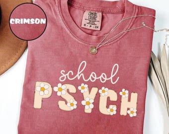 May include: A crimson red t-shirt with the text "school psych" in white with daisy flowers around the letters.