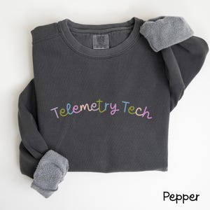 Może przedstawiać: Szara bluza z nadrukiem "Telemetry Tech" w kolorach tęczy. Bluza wykonana jest z miękkiej, wygodnej tkaniny i ma luźny krój.