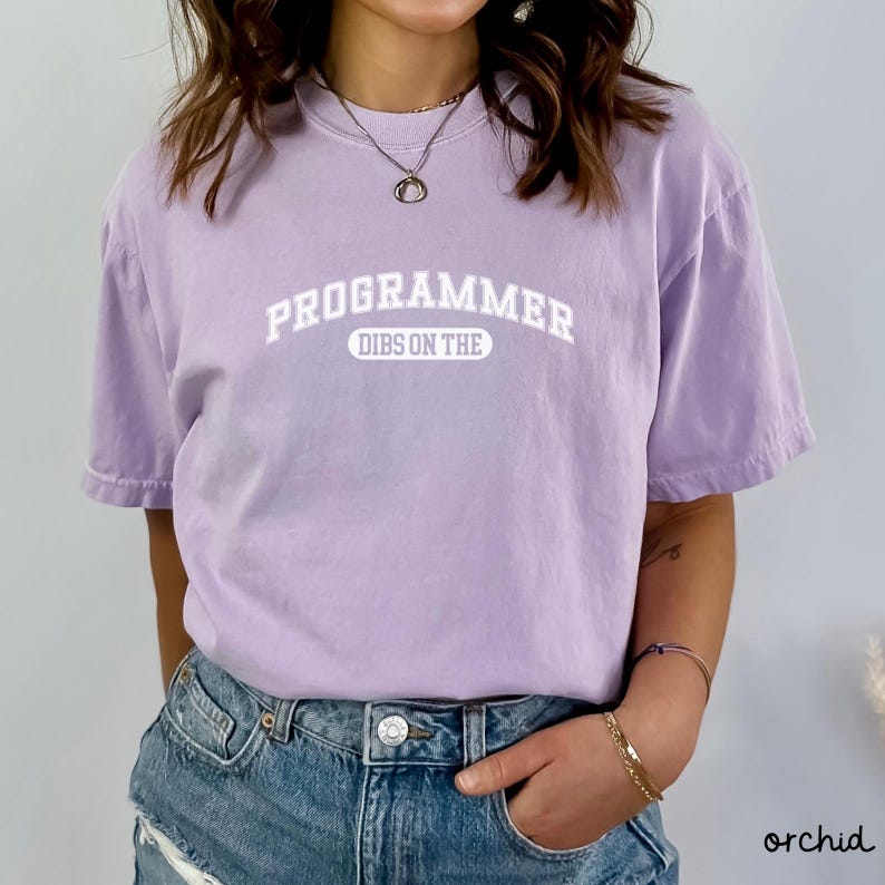May include: A lavender t-shirt with the text "PROGRAMMER DIBS ON THE" in white.