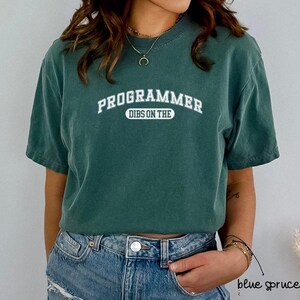 May include: A green t-shirt with white text that reads "PROGRAMMER DIBS ON THE" in an arched font.