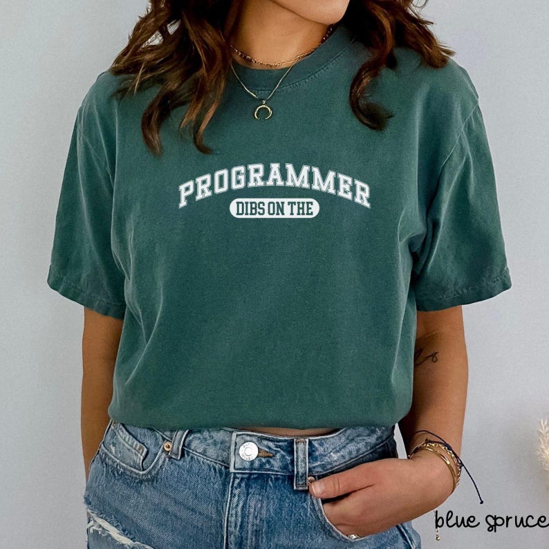 May include: A green t-shirt with white text that reads "PROGRAMMER DIBS ON THE" in an arched font.