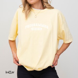 May include: A yellow t-shirt with the text "PROGRAMMER" in white, with the words "OBSESSED" underneath in a smaller font.