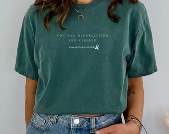 May include: A teal blue t-shirt with the text "Not all disabilities are visible awareness" and a white ribbon.